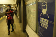 A commuter walks past a TFL (Transport for London) information poster telling passengers that it is compulsory to wear a face mask on public transport to curb the spread of COVID-19, in London, Tuesday, Nov. 30, 2021. The emergence of the new COVID-19 omicron variant and the world's desperate and likely futile attempts to keep it at bay are reminders of what scientists have warned for months: The coronavirus will thrive as long as vast parts of the world lack vaccines.(AP Photo/Alastair Grant)