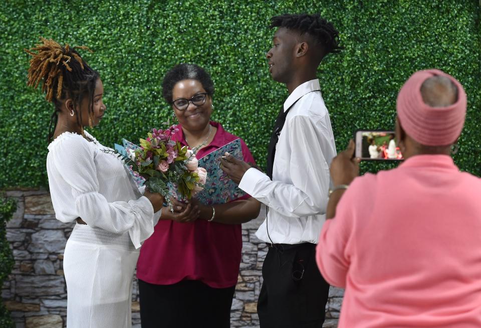 Notary Rosalind Balkcom performs the wedding service for Brianna Cheley and Brian Dunn as Dunn's grandmother Jacqueline Yulee videos the service. The bride and groom met as students at Terry Parker High School and have been together more than six years.