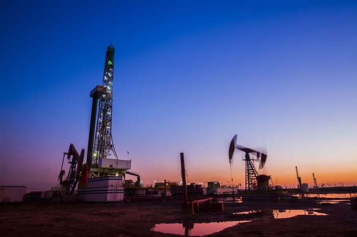 Drilling rig and pumpjack at dusk.