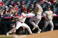 Oakland Athletics' Seth Brown, center, safely takes first base as Los Angeles Angels first baseman Jared Walsh, left, fields a throw during the 10th inning of a baseball game Sunday, Sept. 19, 2021, in Anaheim, Calif. (AP Photo/Jae C. Hong)