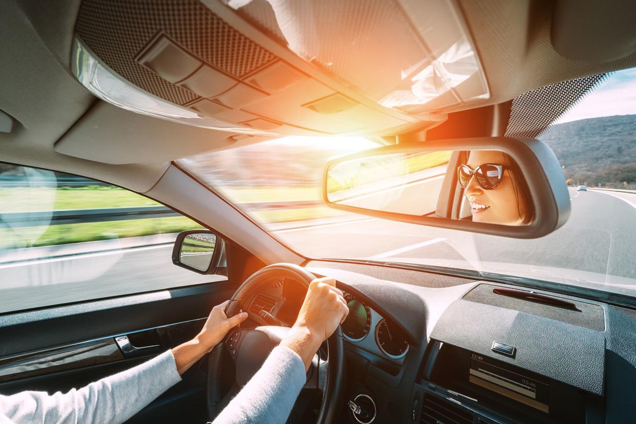 woman drive a car reflects in back view mirror