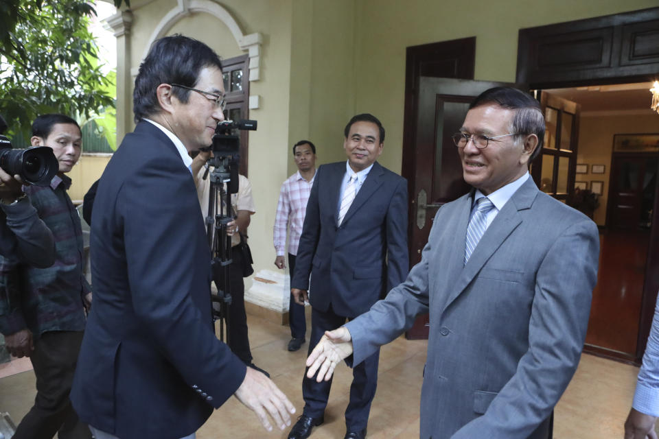 Japanese Ambassador Masahiro Mikami, front left, shakes hands with the banned Cambodia National Rescue Party's President Kem Sokha before a meeting at his house in Phnom Penh, Cambodia, Wednesday, Nov. 13, 2019. Kem Sokha was freed Sunday by court order after more than two years in detention without trial. (AP Photo/Heng Sinith)