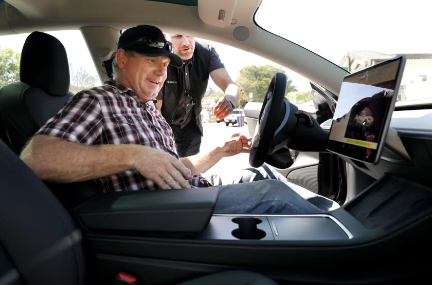 Brian Pennington, left, takes delivery his Tesla Model 3 from Trevor Enge, head of fleet management for Autonomy.