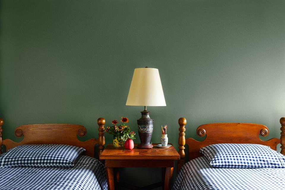 a bedroom with two twin beds and a green wall