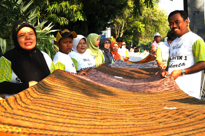 Hand in hand: Up to 6,600 people comprising the school's students, teachers and alumni were involved in spreading the fabric, which was made from thousands of regular-size batik cloths. (