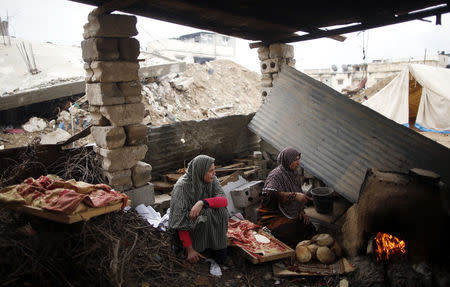 Palestinian woman bake bread at their makeshift shelter near the ruins of their house that witnesses said was destroyed by Israeli shelling during a 50-day war last summer, east of Gaza City February 18, 2015. REUTERS/Mohammed Salem