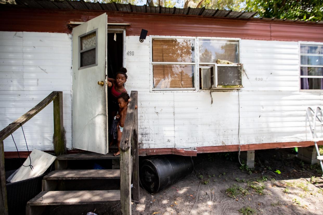 Jakeila, 9, and her little brother Nathaniel, 2, peek their heads out the door of their home in Jasper, Florida Wednesday, July 6, 2022.