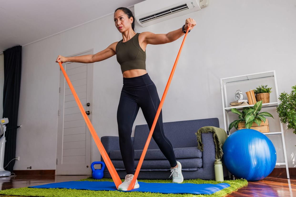 woman using resistance band at home in living room