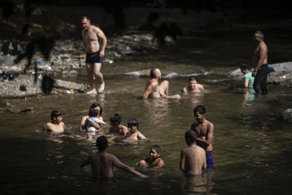 Migrants bathe in a stream near Las Tecas camp, from where they will start walking across the Darien gap from Colombia to Panama in hopes of reaching the US, in Acandi, Colombia, Monday, May 8, 2023. (AP Photo/Ivan Valencia)