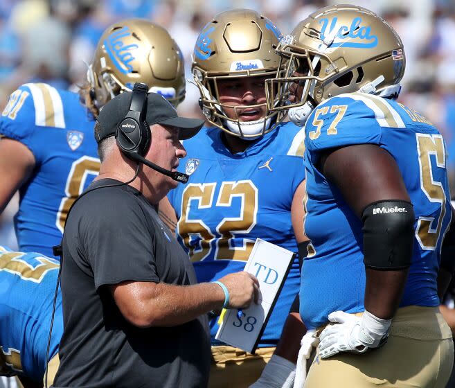 UCLA coach Chip Kelly talks with his players on the sideline during a 2022 game