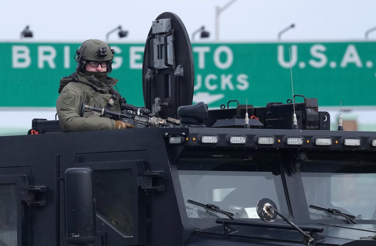 An Ontario Provincial Police tactical officer looks on from the top hatch of an armoured vehicle during protests against COVID-19 restrictions at the Ambassador Bridge on Feb. 12, 2022. THE CANADIAN PRESS/Nathan Denette