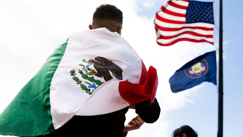 The American flag waves above an attendee wrapped in the Mexican flag at the “I Stand with All Immigrants Rally” in front of the Utah Capitol in Salt Lake City on Saturday, Oct. 28, 2023.