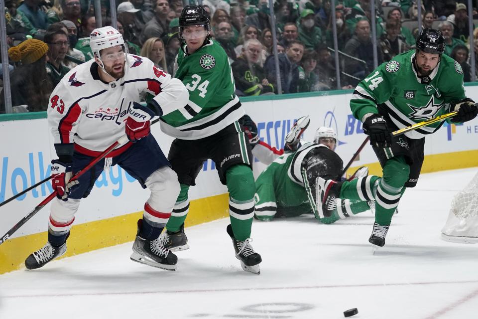 Washington Capitals right wing Tom Wilson (43), Dallas Stars right wing Denis Gurianov (34) and left wing Jamie Benn (14) chase after a loose puck in the first period of an NHL hockey game in Dallas, Friday, Jan. 28, 2022. (AP Photo/Tony Gutierrez)