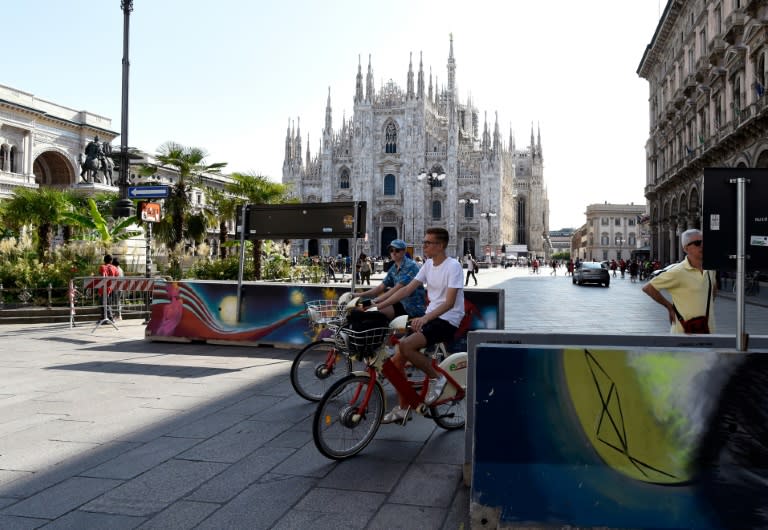 People on bikes weave through concrete barriers placed at the Piazza del Duomo in Milan as security is boosted after the attacks in Spain