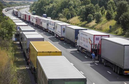 Drivers wait next to their parked lorries on the M20 motorway, which leads from London to the Channel Tunnel terminal at Ashford and the Ferry Terminal at Dover, as part of Operation Stack in southern England, Britain July 31, 2015. REUTERS/Neil Hall