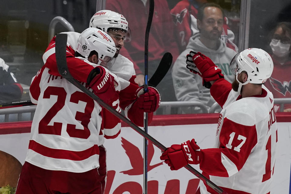 Detroit Red Wings right wing Lucas Raymond (23), center Dylan Larkin (71) and defenseman Filip Hronek (17) celebrate the game-wining goal by Larkin after an NHL hockey game against the Washington Capitals, Wednesday, Oct. 27, 2021, in Washington. The Red Wings won 3-2 in overtime. (AP Photo/Alex Brandon)