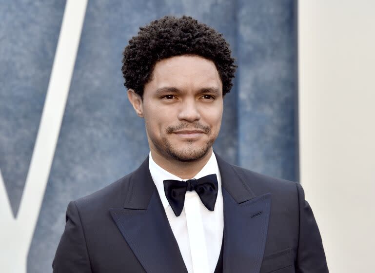 Trevor Noah giving a slight grin while wearing a dark blue tuxedo with a black bowtie