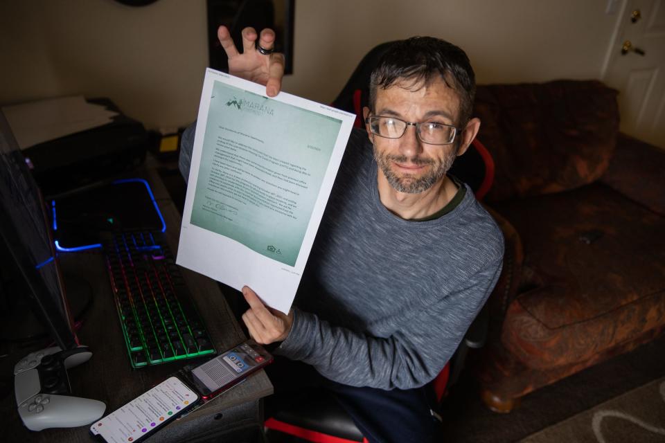 Jason Edwards poses for a photo holding a copy of a notice management left on his door at Marana Apartments. Per federal law, residents like Edwards who were already living at the property in October 2020 have until October 2024 before their rents can be increased to market rate.