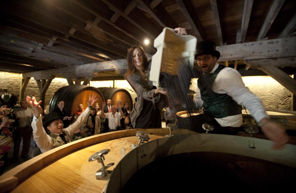 In this photo taken Friday, Aug. 31, 2012 Jean-Charles Boisset, left, cheers as some of the first grapes are dropped into a fermenter during a celebration of the re-birth of Buena Vista winery's historic champagne cellars and caves at the winery in Sonoma, Calif. Many people think the California wine world came of age in 1976 after a famous tasting in Paris put the Golden State’s vintages on the world map. But for Boisset, new owner of the state’s oldest commercial winery, the state’s fine wine making traditions started a century before that. That’s why the Burgundian is building the future of 155-year-old Buena Vista Winery, a landmark known as the birthplace of California wine, on its past. Wines will be made in the stately stone buildings and old wine caves for the first time in two decades. At right is winemaker Brian Maloney and Mary Orlin is center. (AP Photo/Eric Risberg)