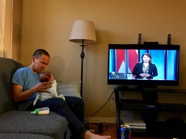 Former CBC North reporter Jordan Konek watches Allakariallak on Northbeat with his newborn. 'If you look at the spectrum, the broadness, the vast lands of Inuit, I don't think we represent them very well in this corporation,' Allakariallak said of the broadcaster's programming.