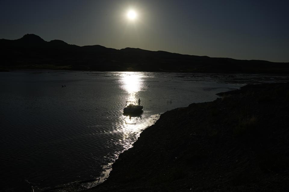 The setting sun reflects off the water of Lake Mead as people stand in a boat near the shore at the Lake Mead National Recreation Area, Friday, Jan. 27, 2023, near Boulder City, Nev. Competing priorities, outsized demands and the federal government's retreat from a threatened deadline all combined to thwart a voluntary deal last summer on how to drastically cut water use from the parched Colorado River, according to emails obtained by The Associated Press. (AP Photo/John Locher)