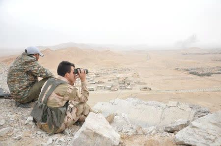 Forces loyal to Syria's President Bashar al-Assad take positions on a look-out point overlooking the historic city of Palmyra in Homs Governorate in this handout picture provided by SANA on March 27, 2016. REUTERS/SANA/Handout via Reuters