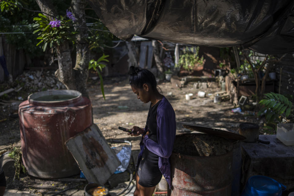 Maria Carla Milan Ramos, wife of Yosney Emilio Román Rodríguez, who is in prison with his two siblings, accused of participating in the recent protests against the government, looks at her cell phone in the patio of their home in the La Guinera neighborhood of Havana, Cuba, Wednesday, Jan. 19, 2022. Six months after surprising protests against the Cuban government, more than 50 protesters who have been charged with sedition are headed to trial and could face sentences of up to 30 years in prison. (AP Photo/Ramon Espinosa)