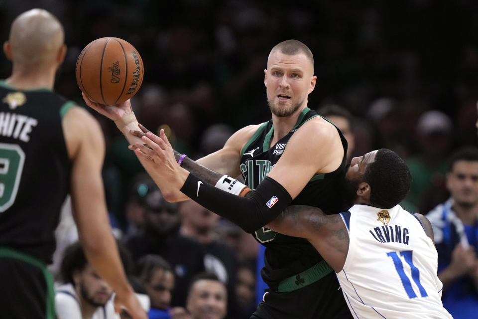 Boston Celtics center Kristaps Porzingis looks to pass while defended by Dallas Mavericks guard Kyrie Irving (11) during the second half of Game 2 of the NBA Finals basketball series, Sunday, June 9, 2024, in Boston. (AP Photo/Steven Senne)
