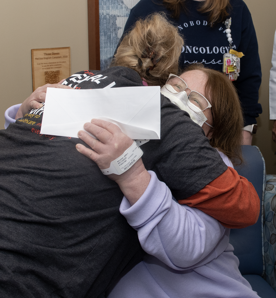 Nicole Deem-Faust, a lab tech at UH Portage Medical Center's Seidman Cancer, hugs Debra Holloway after she receives a check from the Kent Police Department, which raises money each year to help local cancer patients.