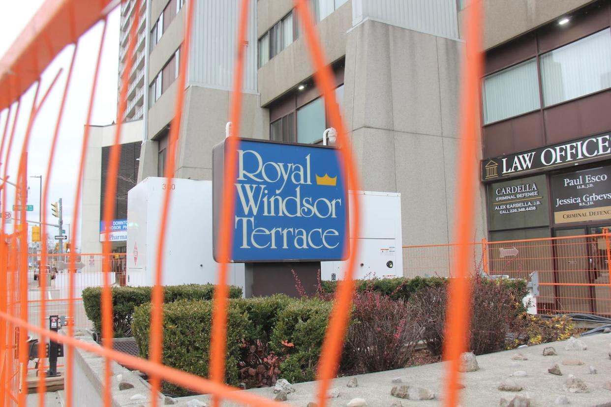 Construction fencing surrounds a sign for the Royal Windsor Terrace, which has generator power but still no heat for much of the building after the collapse of the hydro vault in September.  (Michael Evans/CBC - image credit)