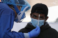 FILE - In this July 24, 2020 file photo, Dr. Diana Pacheco explains to a patient that she will collect nasal and throat swabs, during walk-up COVID-19 testing in a mobile diagnostic tent, in San Gregorio Atlapulco in the Xochimilco district of Mexico City, Friday, July 24, 2020. The capital's health secretariat erected mobile testing units in the areas of the city hardest hit by the coronavirus pandemic, but only limited numbers of testing kits are available each day. (AP Photo/Rebecca Blackwell, File)