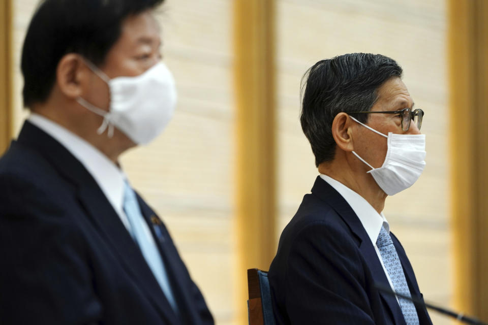 President of the Japan Community Healthcare Organization Shigeru Omi, right, attends a government task force meeting on the COVID-19 measures at the prime minister's office Friday, April 9, 2021, in Tokyo. Japan announced Friday that it will raise the coronavirus alert level in Tokyo to allow tougher measures to curb the rapid spread of a more contagious variant ahead of the Summer Olympics. (AP Photo/Eugene Hoshiko, Pool)