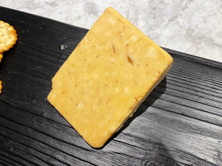 Yellow block of figgy cheddar on a black cutting board