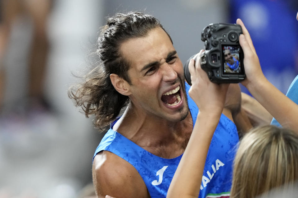Gianmarco Tamberi, of Italy, celebrates into the camera of supporters own the tribune after winning the Men's high jump final during the World Athletics Championships in Budapest, Hungary, Tuesday, Aug. 22, 2023. (AP Photo/Martin Meissner)