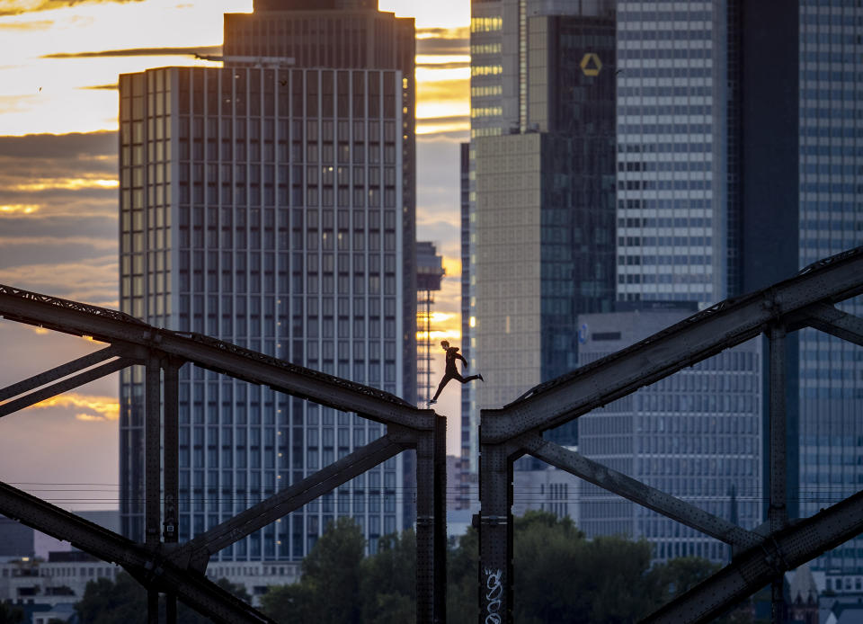 A parkour runner jumps on a railway bridge with the buildings of the banking district in background in Frankfurt, Germany, on Sept. 9, 2020. (AP Photo/Michael Probst)