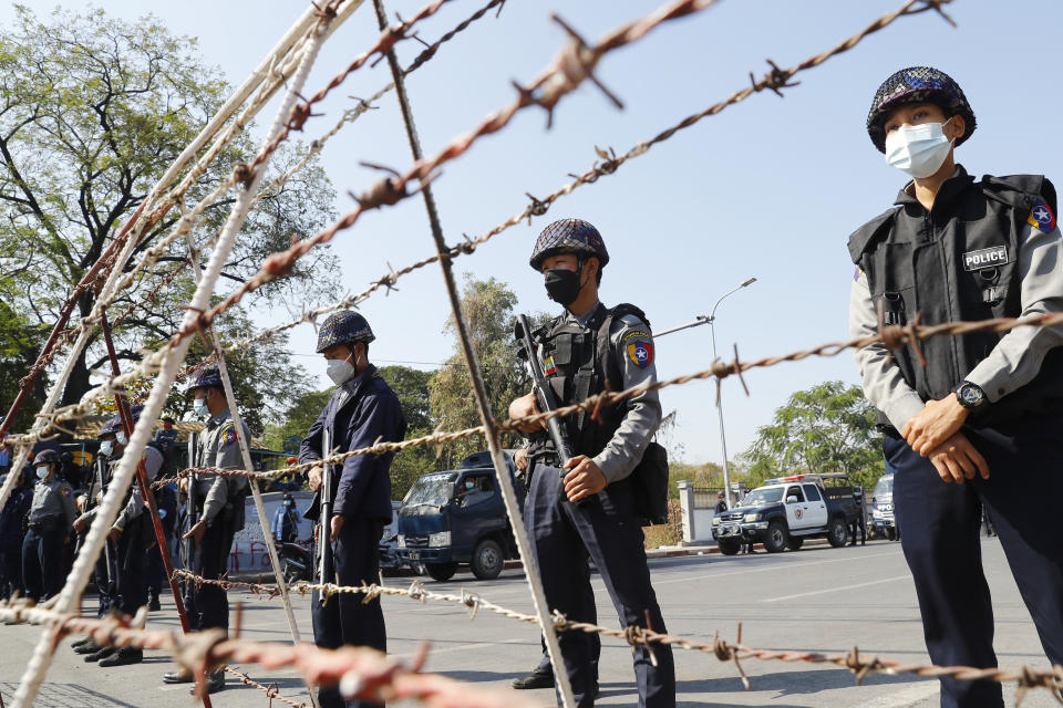 Police officers stand behind barbed-wire blocking protesters during a demonstration in Mandalay, Myanmar, Tuesday, Feb. 9, 2021. Protesters continued to gather Tuesday morning in major cities breaching Myanmar's new military rulers ban of public gathering of five or more issued on Monday intended to crack down on peaceful public protests opposing their takeover. (AP Photo)