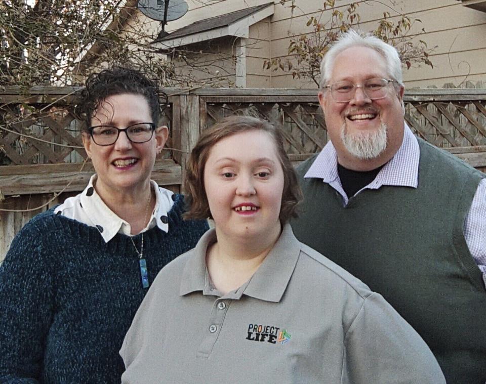In this photo from November 2023 image provided by Marvin J. Miller, , Teresa Miller, left, Lilly Miller, center, and Marvin Miller, pose on the back porch of their home in Wichita, Kan. Lilly Miller, now 21, has Down syndrome and has been on a state waiting list for a day program and other services for 10 years. (Marvin J. Miller via AP)