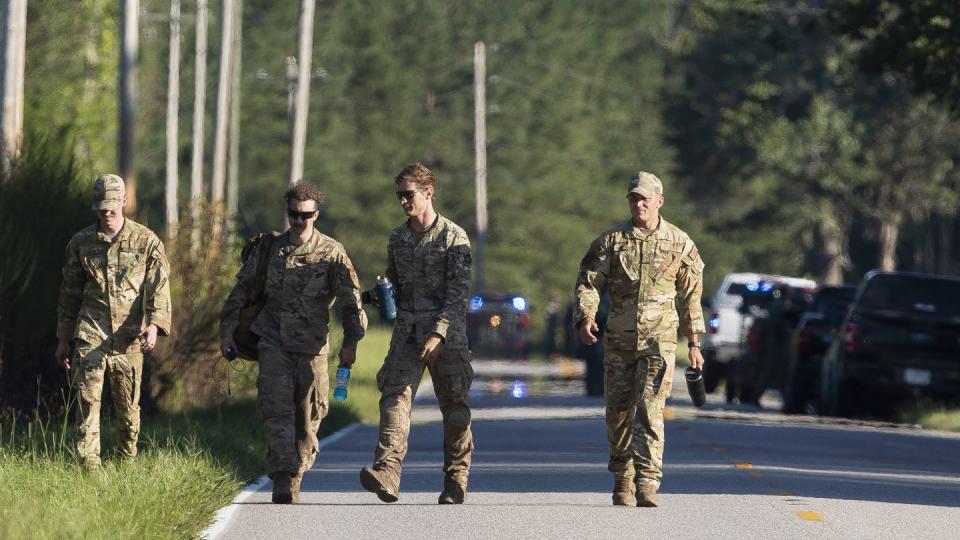 Airmen from Joint Base Charleston walk down Old Georgetown Road when setting up a base during the recovery process for an F-35 that crash landed in a field nearby in Williamsburg County, S.C., on Monday, Sept. 18, 2023. (Henry Taylor/The Post And Courier via AP)