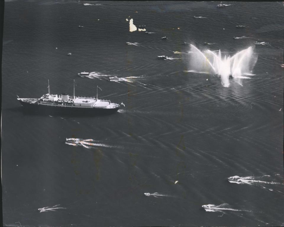 Small boats trail the Britannia, carrying Britain's Queen Elizabeth, past Milwaukee on July 7, 1959. The fireboat Deluge was engulfed in its own spray when it saluted the queen with a watery display. Sixty small craft sailed out to greet the royal yacht.