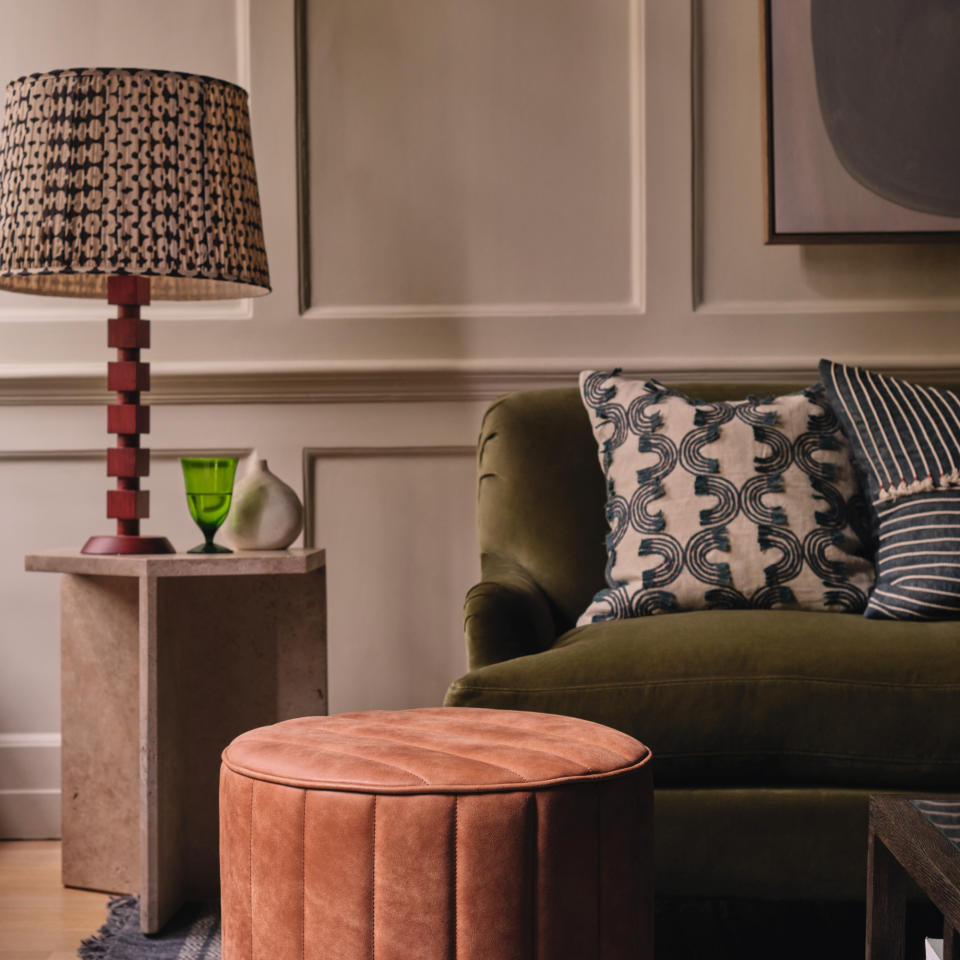 Sculptural side table with table lamp in living room next to sofa