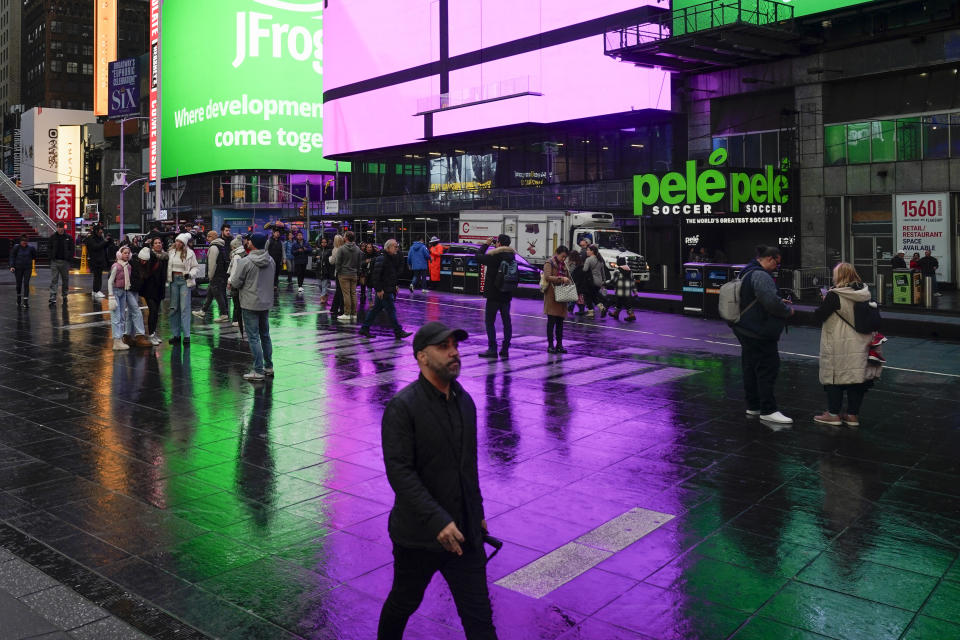 Pedestrians walk through a wet Times Square in New York, Monday, Dec. 18, 2023. A storm moving up the East Coast brought heavy rain and high winds to the Northeast on Monday, threatening flooding, knocking out power to hundreds of thousands, and forcing flight cancelations and school closings. (AP Photo/Seth Wenig)