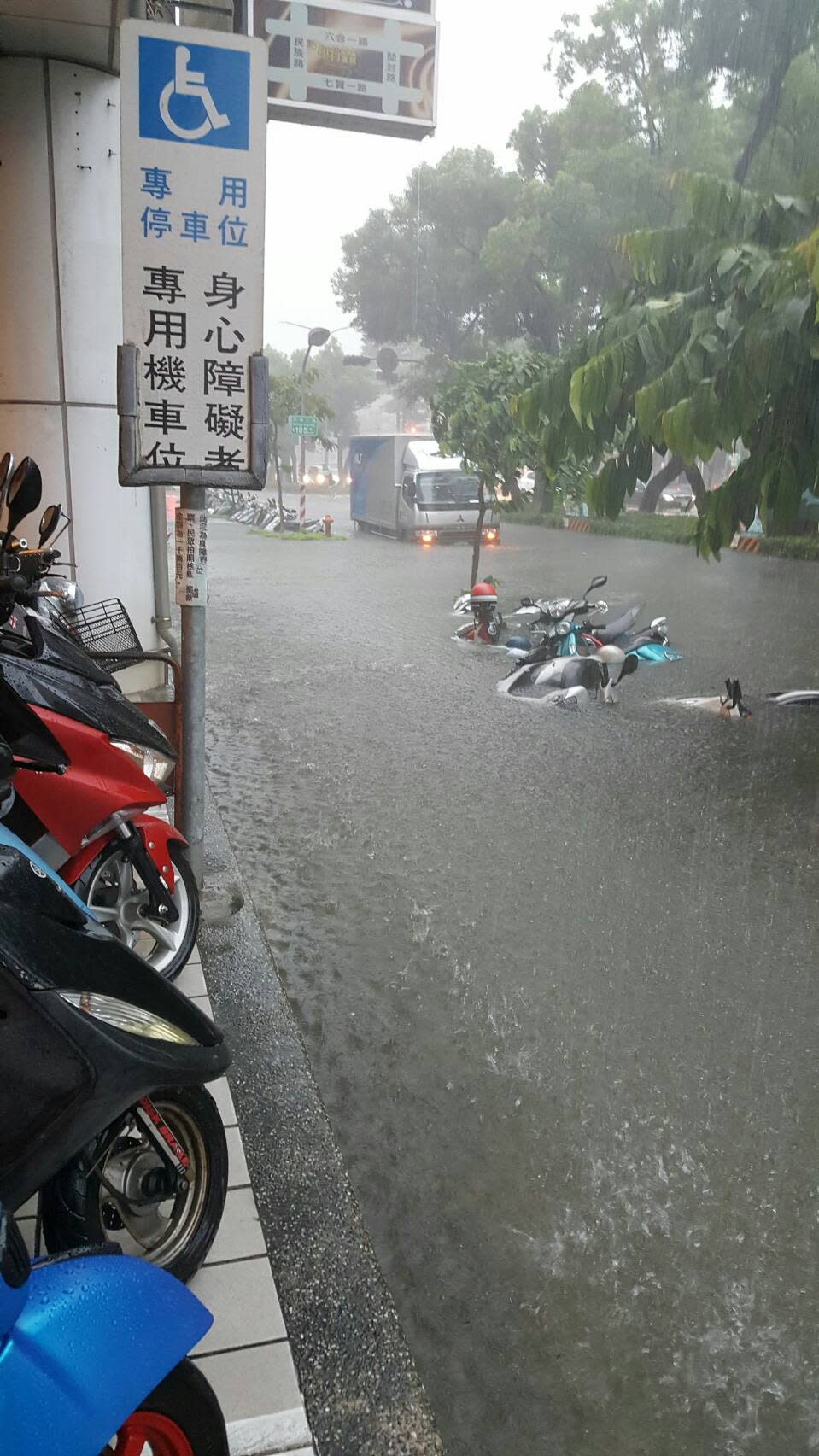 高雄市23日瞬間強降雨不斷，造成多處積水盈尺，路上多部汽機車拋錨，交通打結，圖為新興區民生路淹水一景。（中央社/警方提供）