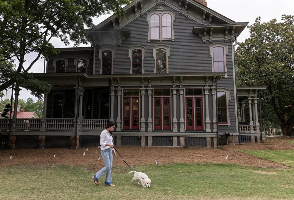 Tina Konidaris walks with Clementine, her family’s English Cream Golden Retriever puppy, outside the Andrews-Duncan House on Thursday, May 25, 2023, in Raleigh, N.C. Konidaris and her partner, Jeff Turpin, moved into the nineteenth century house in February after working to renovate it for about five years.