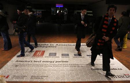 Commuters walk over an advertisement promoting Canada as a preferable oil provider for America at a metro station in Washington January 29, 2014. REUTERS/Yuri Gripas