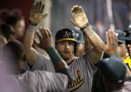 Oakland Athletics' Craig Gentry, center, is greeted by teammate after he scored on a wild pitch by Los Angeles Angels starting pitcher Garrett Richards during the seventh inning of a baseball game on Tuesday, April 15, 2014, in Anaheim, Calif. (AP Photo/Jae C. Hong)