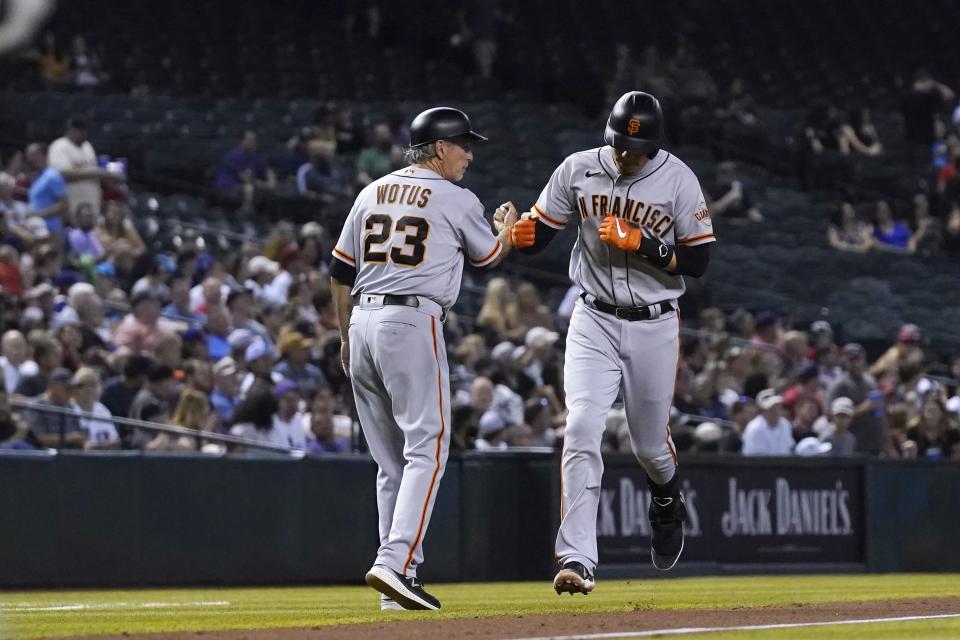 San Francisco Giants' Wilmer Flores, right, celebrates his two-run home run against the Arizona Diamondbacks with third base coach Ron Wotus (23) during the fourth inning of a baseball game Thursday, July 1, 2021, in Phoenix. (AP Photo/Ross D. Franklin)