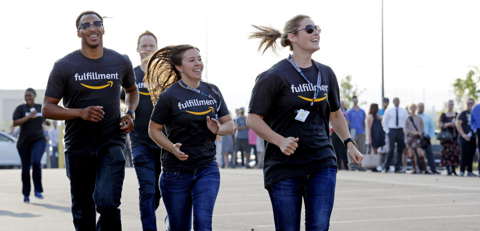 Amazon workers run past a line of applicants waiting to enter a job fair, Wednesday, Aug. 2, 2017, at an Amazon fulfillment center, in Kent, Wash. (AP Photo/Elaine Thompson)