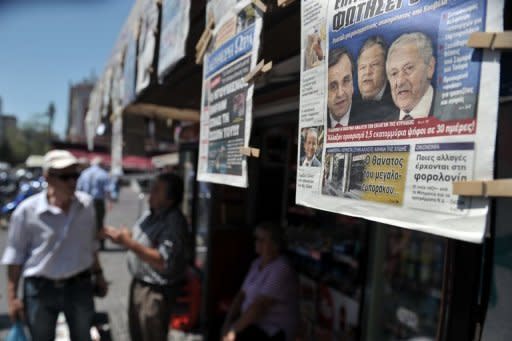 Pedestrians walk past a news-stand in Athens. Conservative leader Antonis Samaras has been sworn in as the prime minister of new Greek coalition, taking up the challenge of trying to revise the terms an unpopular EU-IMF bailout deal