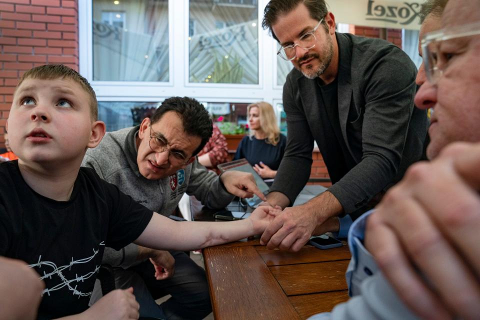 Artem Sokolov, 11, of Kharkiv, Ukraine, left, who was injured in a cluster bomb blast within the last year that left him in a coma for three months and with severe nerve damage in his left arm, gets screened for surgery at a hotel in Leczna, Poland, on May 14 by Dr. Gennadiy Fuzaylov, a pediatric anesthesiologist at Massachusetts General Hospital and founder of Doctors Collaborating to Help Children and Dr. Shawn Diamond, an assistant professor of plastic surgery at Texas Tech in El Paso and Dr. David Brown a plastic surgeon from the University of Michigan.