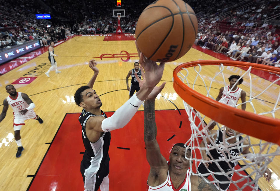 San Antonio Spurs' Victor Wembanyama, left, shoots as Houston Rockets' Jabari Smith Jr. defends during the first half of an NBA basketball game Tuesday, March 5, 2024, in Houston. (AP Photo/David J. Phillip)